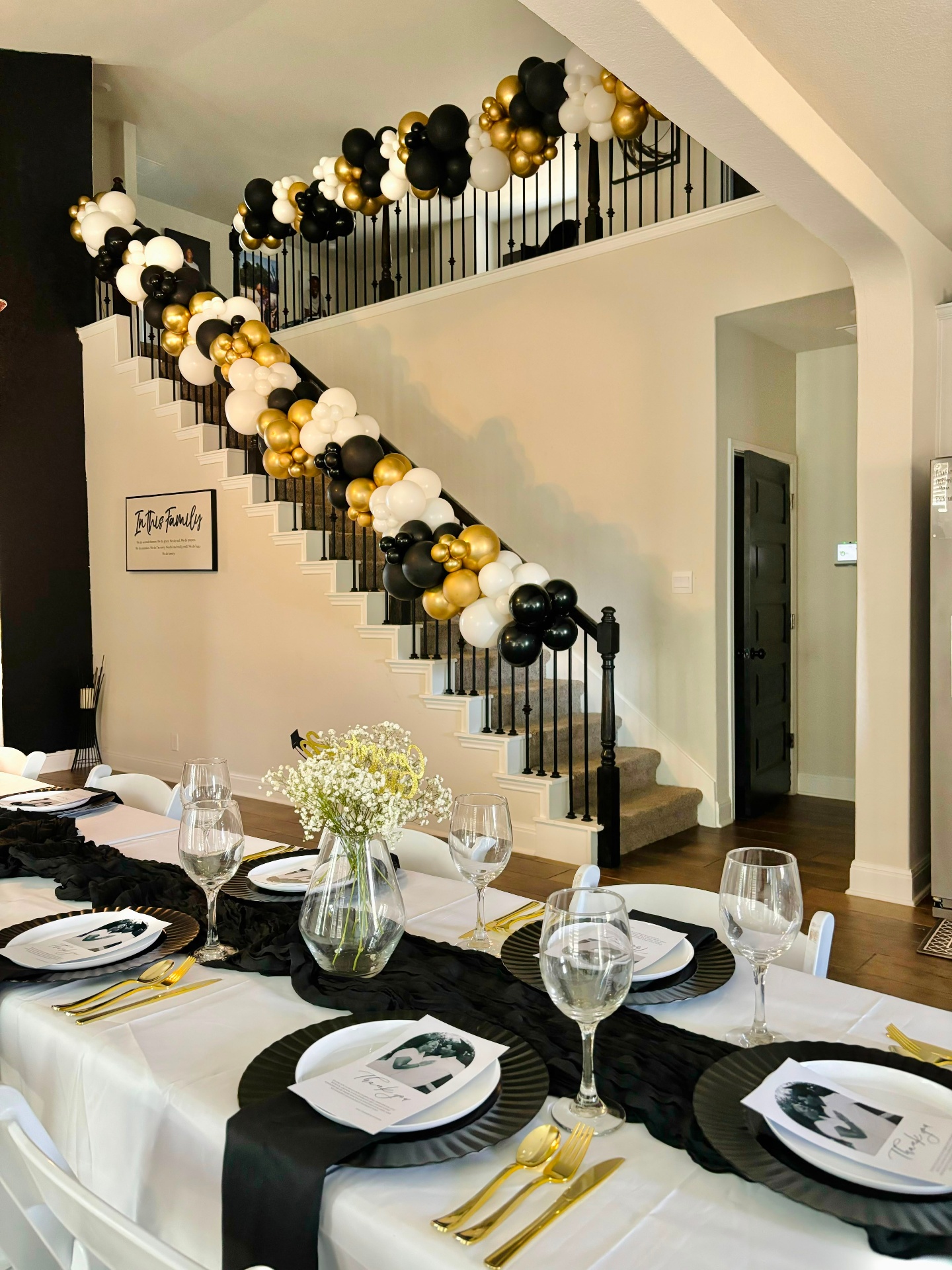 Black, white & gold balloon garland draping a luxury staircase with a formal tablescape by LUX Event Design